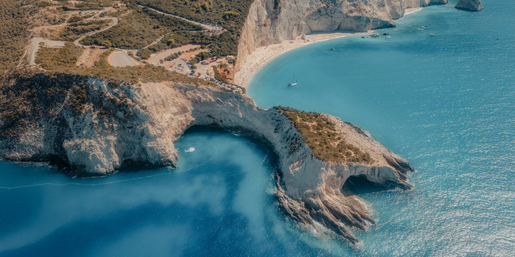 Aerial view of blue sea, mountains, white sandy beach at sunrise in summer. Porto Katsiki, Lefkada island, Greece. Beautiful landscape with sea coast, yacht, rocks, azure water, green forest. Top view